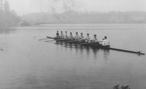 A black and white photo of a rowing team on a lake.